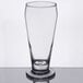 A close up of a Libbey footed pilsner glass with a clear liquid in it.