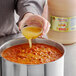 A person pouring Marie Sharp's Grapefruit Pulp Habanero Hot Sauce into a pot of food.