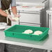 A person wearing gloves in a school kitchen using a green Baker's Mark polypropylene dough proofing box to hold dough.
