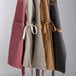 Acopa Hazleton canvas bib aprons hanging on a rack in a professional kitchen.