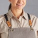 A woman wearing an Acopa Hazleton canvas apron with brown straps.