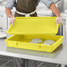 A person wearing a chef's uniform holding a yellow Baker's Mark dough proofing box lid.