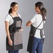 Two women wearing black and grey Backyard Pro canvas grilling aprons with utility pockets.