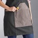 A woman wearing a black Backyard Pro grilling apron with a pocket.