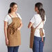 Two women wearing brown Acopa Hazleton canvas bib aprons.