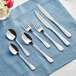 Acopa stainless steel spoons on a blue cloth.