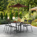 A Lancaster Table & Seating wood patio table with a cinnamon umbrella on it.