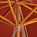 A close up of a Lancaster Table & Seating wood umbrella with a red canopy.