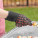 A person grilling food while wearing a Mr. Bar-B-Q silicone oven glove.