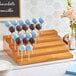 A dark brown wood Acopa Mesa skewer and cake pop holder with chocolate and blue cake pops on it.