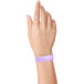 A person's hand wearing a light purple Carnival King wristband.