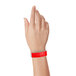 A person holding a red Carnival King Tyvek wristband.