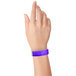 A person holding a neon purple Carnival King wristband.