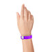A hand wearing a purple Carnival King wristband with a silver clasp.