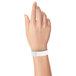 A hand holding a white Carnival King wristband.