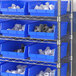 A metal shelving unit with Regency blue plastic bins on the shelves.
