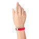 A person holding a red Carnival King wristband.