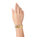 A woman's hand wearing a Carnival King gold wristband.