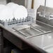 A white dish rack with dishes in an Advance Tabco pre-rinse basket.