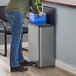 A person in blue jeans uses a Rubbermaid metal dual stream step-on trash can to put a blue plastic bag in a blue container.