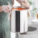 A person in gloves holding a Choice stainless steel bain marie pot full of soup.