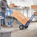 A person pushing a blue Lavex hand truck with boxes.