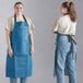 Two women wearing Choice navy blue aprons over jeans.