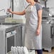 A woman in a white Choice Lightweight Vinyl dishwasher apron washing dishes.