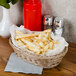 A honey oval plastic basket filled with french fries on a table.