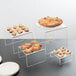 A set of clear acrylic display risers holding desserts on a table.