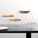 A table with three clear acrylic risers holding pastries on display.