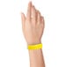A close-up of a hand wearing a yellow Carnival King Tyvek wristband.