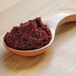 A wooden spoon filled with Organic Blackberry Powder.