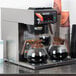 A Bunn automatic coffee brewer with three coffee pots on top.