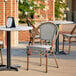 A Lancaster Table & Seating black and white outdoor side chair with a wooden frame on a patio.