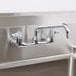 A close up of an Equip by T&S wall mounted faucet with swing spout and lever handles.