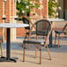 A Lancaster Table & Seating French Bistro Black Outdoor Side Chair on a patio with a table.