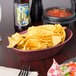 A raspberry polyethylene oval basket filled with tortilla chips on a table.