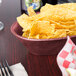 A raspberry polyethylene oval basket filled with chips on a table in a Mexican restaurant.