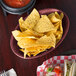 A table with oval raspberry polyethylene baskets filled with tortilla chips and salsa.
