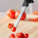 A Schraf serrated tomato knife cutting a tomato over a bowl.