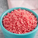 A bowl of Dutch Treat strawberry krunch topping with pink granules.