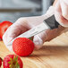 A person in gloves using a Schraf Smooth Edge Paring Knife to cut a strawberry.