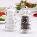 A Chef Specialties Laurel acrylic salt shaker and pepper mill set. Two clear pepper grinders with salt and pepper inside.