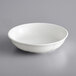 An Acopa Condesa scalloped porcelain fruit dish in white on a gray surface.