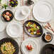 A table with an Acopa Condesa matte gray scalloped platter, white plates, and food.