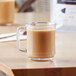 A glass mug of Arrosto Nicaragua Jinotega whole bean coffee on a wooden table.