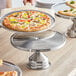 A pizza on a stainless steel platter with a mirror finish.