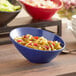 A blue Acopa melamine bowl with pasta and salad on a table.