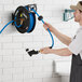 A man using a Regency powder-coated steel hose reel with a spray water gun to clean.